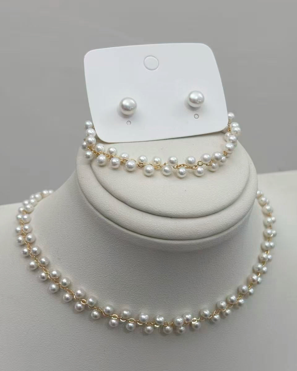 A pearl choker and matching bracelet with staggered pearls along gold-tone chains, displayed with small round pearl stud earrings.
