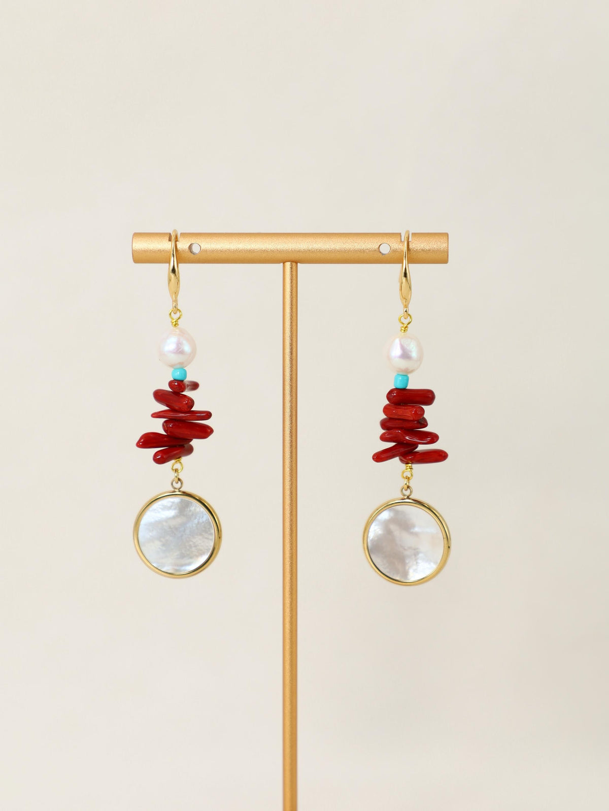 Scarlet Orbit Earrings hanging on a gold display stand